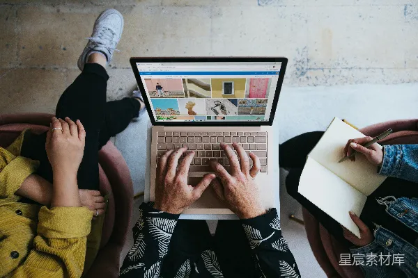 高清摄影 一个人在腿上使用微软Surface Laptop，旁边还有另外两个人。