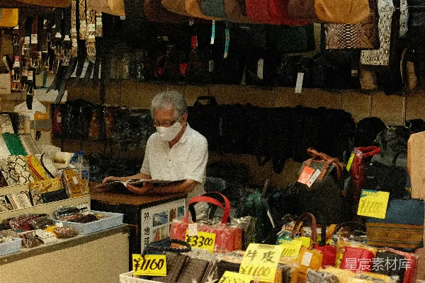 高清摄影 一个男人站在一个装满袋子的商店前面。