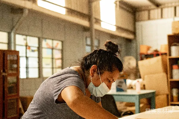 高清摄影 一个戴着口罩的女人正在给床垫套上床垫套。