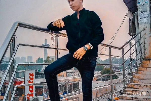 高清摄影 一个男人坐在金属护栏的顶部。