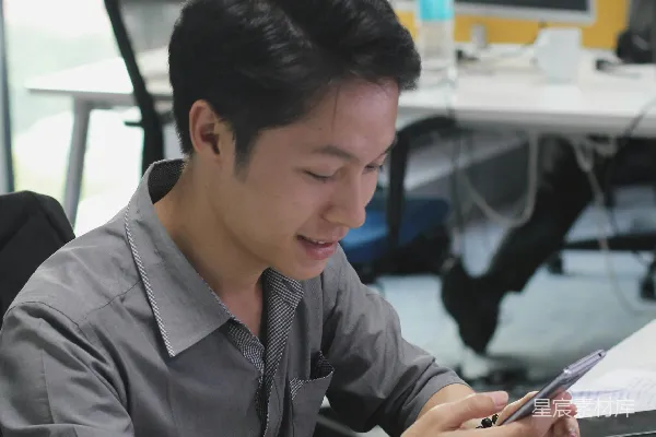 高清摄影 一个男人坐在桌子旁使用手机。