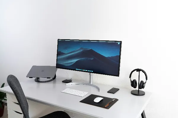 高清摄影 宽屏黑色平板电脑显示器，搭配Apple Magic键盘和鼠标放在桌子上。
