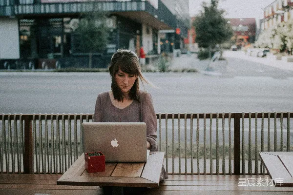 高清摄影 穿灰色衬衫的女人坐在MacBook前面的长椅上。