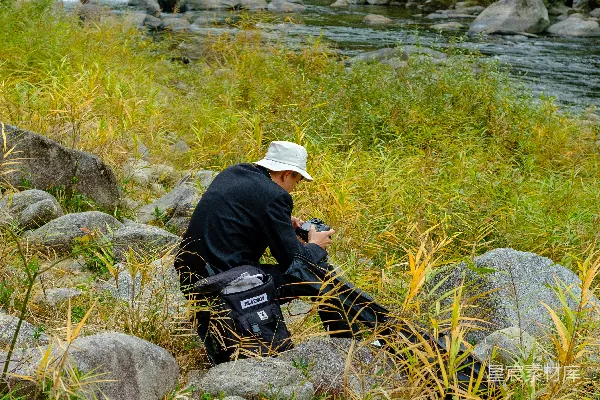 高清摄影 一个男人坐在河边的岩石上。