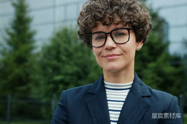 高清摄影 一个有着卷发和戴眼镜的女人微笑着。