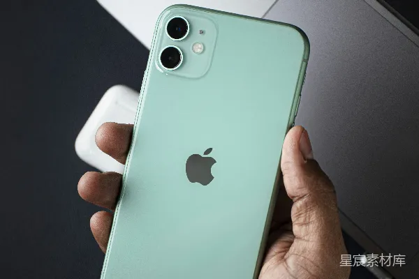 高清摄影 一个人拿着一部iPhone，放在一台笔记本电脑前面。