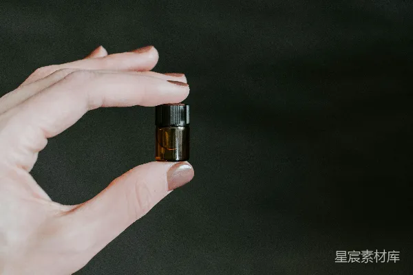 高清摄影 拿着一小瓶棕色带色玻璃瓶的人