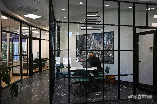 高清摄影 在现代化的办公室会议室里，一名男子正在使用笔记本电脑工作。