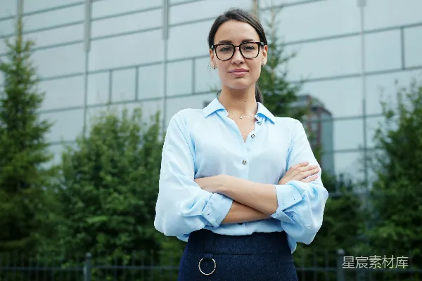 高清摄影 戴眼镜的女士在户外交叉双臂站着。