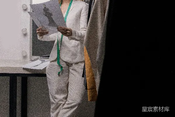 高清摄影 穿着白色西装外套和白色裤子的女性站在一张白色桌子旁边