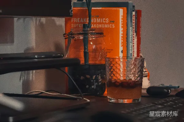 高清摄影 棕色木桌旁的黑色电脑键盘旁边放着一个干净的饮料杯。