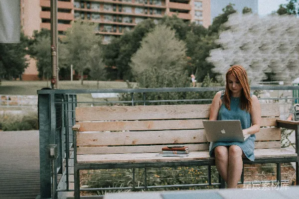 高清摄影 坐在长椅上的白人女性正在使用MacBook Pro。