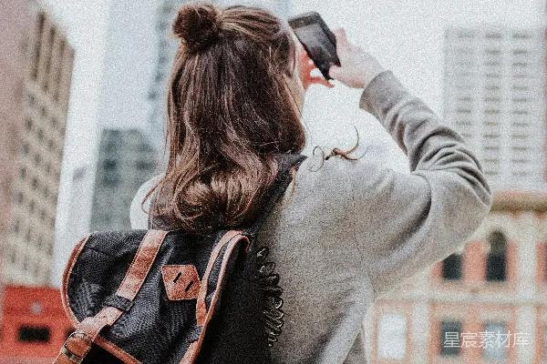 高清摄影 女人正在路边拍摄高楼的照片。