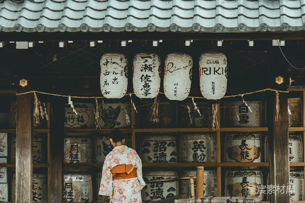 高清摄影 一位穿着橙白相间的和服的女人站在房子附近。