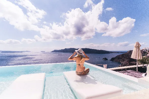 高清摄影 白天，一位女士坐在水边的白色椅子上。