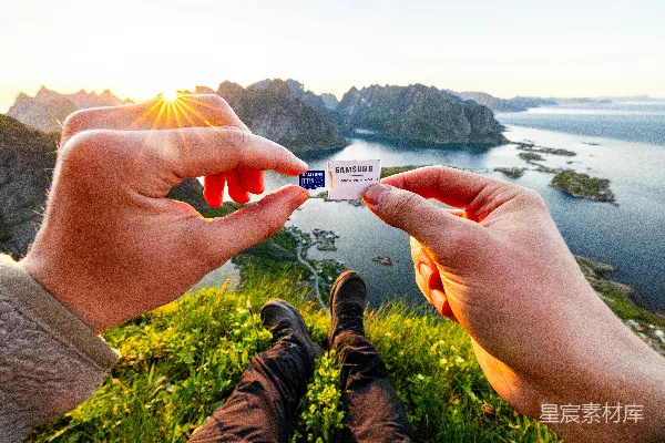 高清摄影 双手拿着SD卡，背景是风景如画的山海景色。