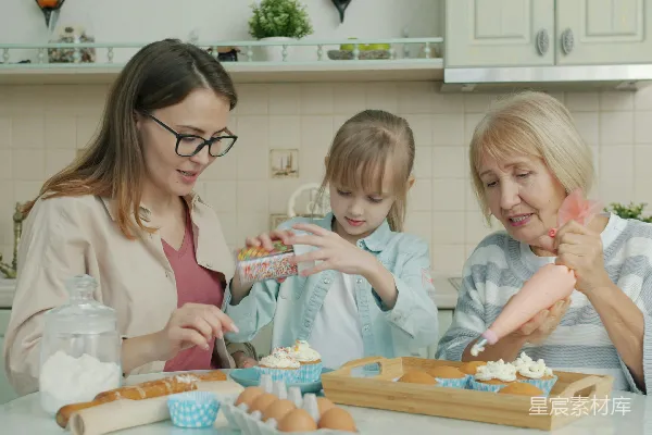 高清摄影 三位女性在厨房里烘焙和装饰纸杯蛋糕。