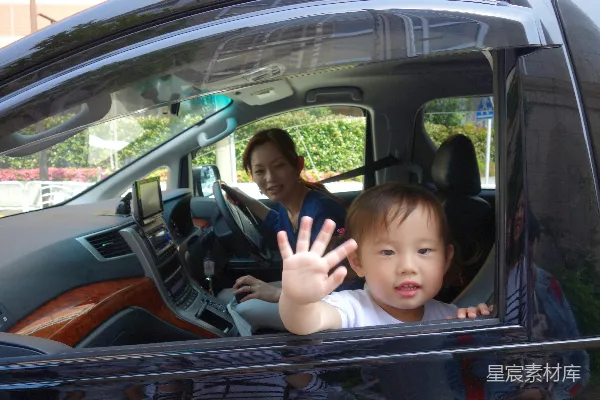 高清摄影 孩子在车窗上挥手，母亲开车。