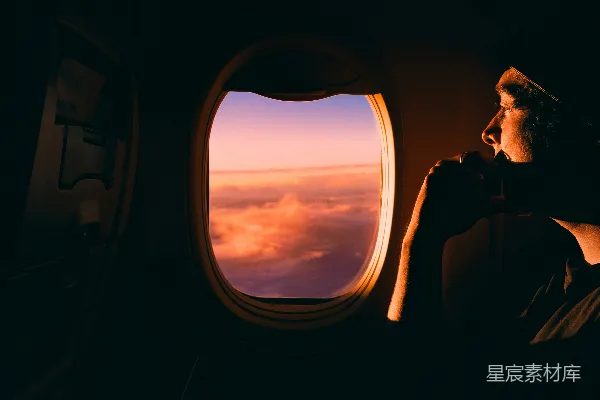 高清摄影 穿着黑色夹克的男人坐在车座上，看向窗外的夕阳。