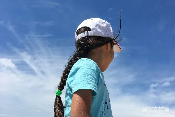 高清摄影 一个小女孩站在海滩上，抬头望着天空。