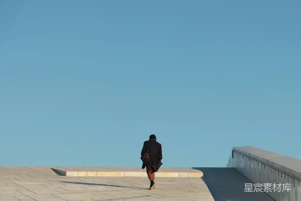 高清摄影 一个穿着黑色夹克的男人站在白天的灰色混凝土地板上。