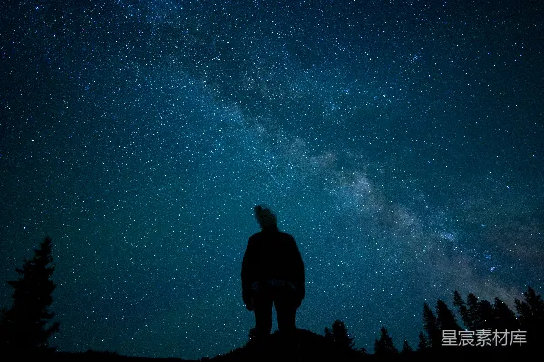 高清摄影 一个男人站在山顶上，脚下是满天星辰的夜空。
