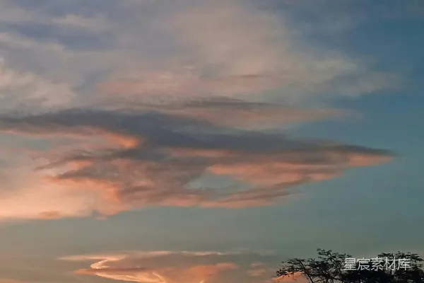 高清摄影 夕阳西下，天空中有云彩，前景是树木。