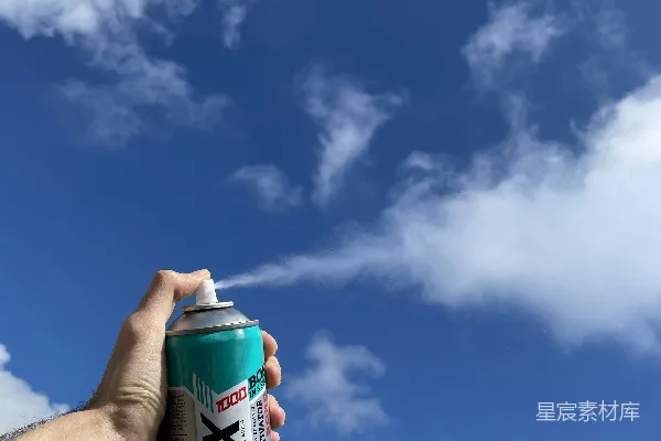 高清摄影 手持绿色和白色喷漆罐的人在白天蓝天下白云间