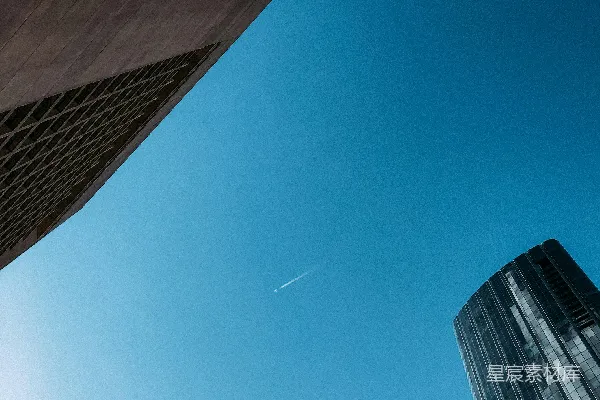 高清摄影 一座高大的建筑物上方，一架飞机在空中飞行。