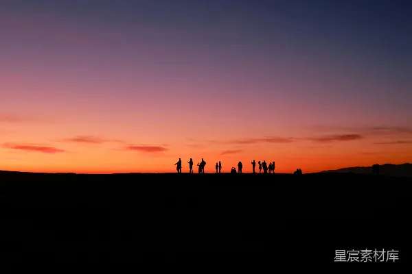 高清摄影 一群人在夕阳下站在山顶上。