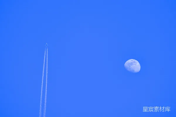 高清摄影 一架飞机在空中飞行，背景中有月亮。