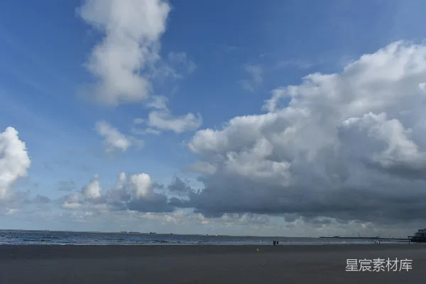 高清摄影 一个在阴云密布的天空下沿着海滩散步的人