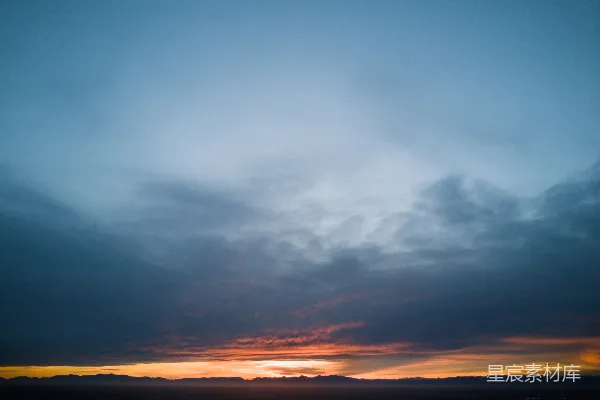 高清摄影 夕阳的天际线上，橙色的余晖下飘着乌云。