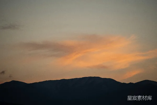 高清摄影 山峰在柔和的橙色夕阳天空下剪影