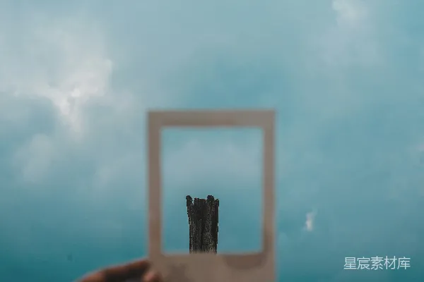 高清摄影 一只手拿着一个方形物体，背景是阴云密布的天空。