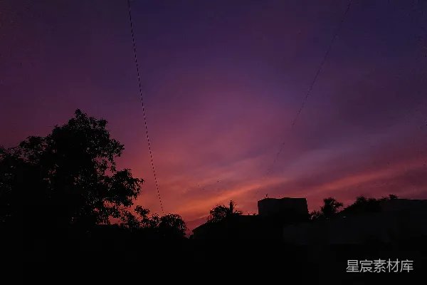 高清摄影 夜晚的天空呈现出紫色和红色，前景中有几根电线。