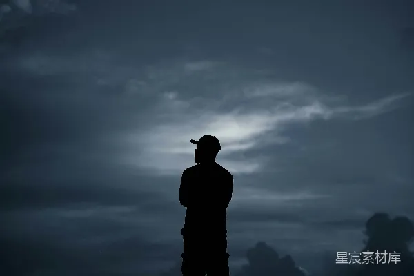 高清摄影 一个人站在山顶的剪影，天空中布满了云层。