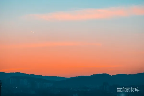 高清摄影 夕阳西下，天空灿烂，山峦在夜色中显得深邃，城市灯火在下方闪烁。