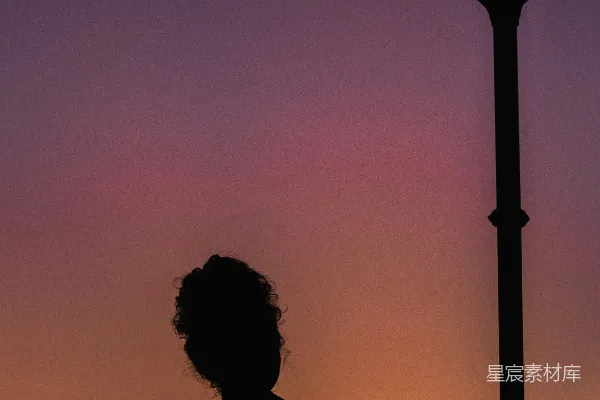 高清摄影 一个女人站在路灯旁边，夕阳西下。