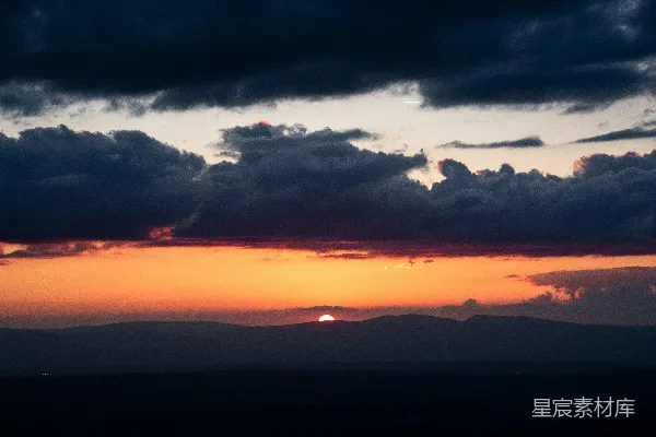 高清摄影 夕阳映照在黑暗的山脉上，云层显得格外壮观。
