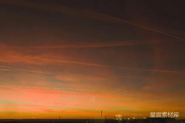 高清摄影 夕阳西下，远处灯光映衬着飞机尾迹。