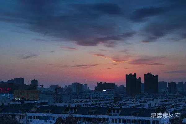 高清摄影 夕阳西下，橙色与灰色的云层下，城市天际线的轮廓清晰可见。