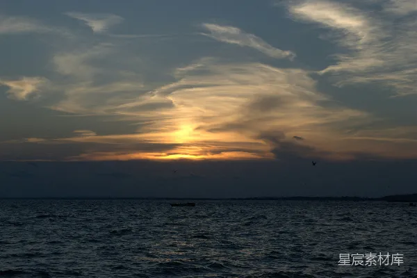 高清摄影 在多云的天空下，夕阳下的水面