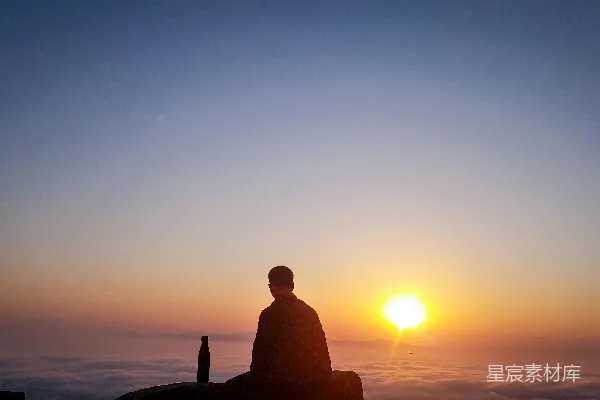 高清摄影 夕阳下，一个人坐在岩石上的剪影