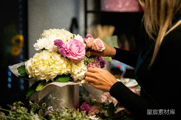 高清摄影 一位女士正在桌子上将花插在花瓶里。