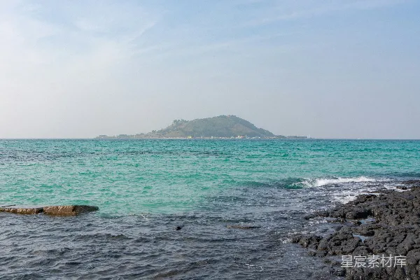 高清摄影 一个岩石海滩，远处有一座大岛。