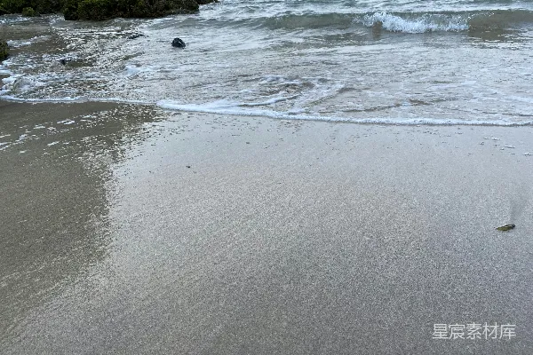 高清摄影 一个沙滩，海浪拍打着岸边。