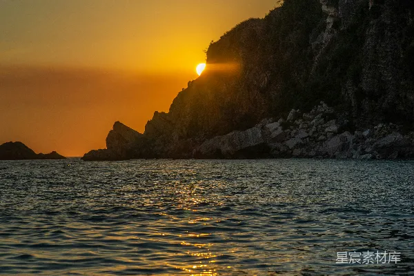 高清摄影 一片水域，岸边岩石嶙峋，夕阳西下。