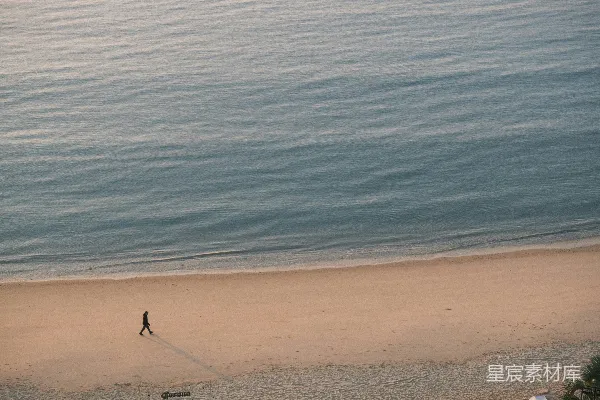 高清摄影 一个正在海滩上散步的人，旁边是海洋。