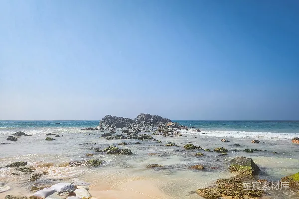 高清摄影 一个带沙子的海滩，岩石和水在蓝天的映衬下。
